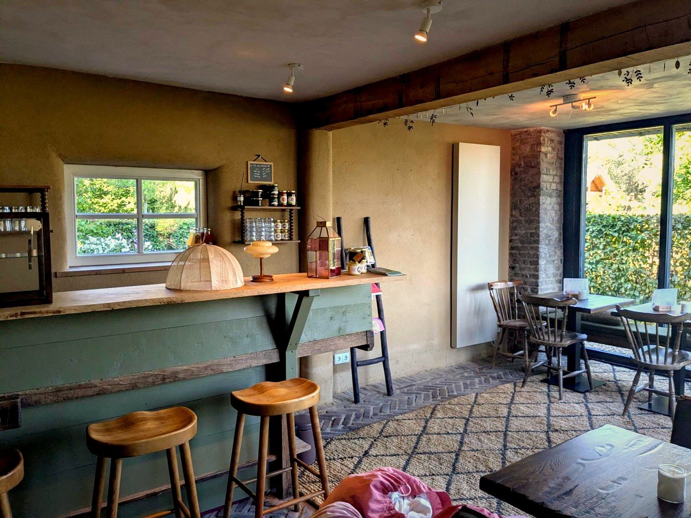 De zaal van 't Leemcafeetje met de groene bar, krukken en tafeltjes bij het raam